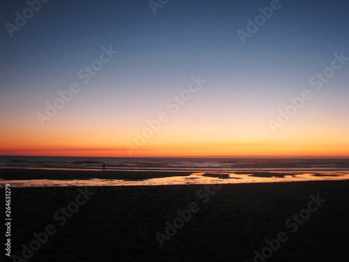 Dark blurred sunset on the sandy shore of the ocean. © Payllik