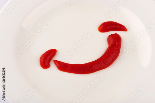 smeared ketchup on a plate in the form of a smile