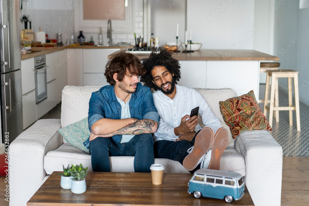 Friends sitting on couch, planning road trip Friends sitting on couch, planning road trip
