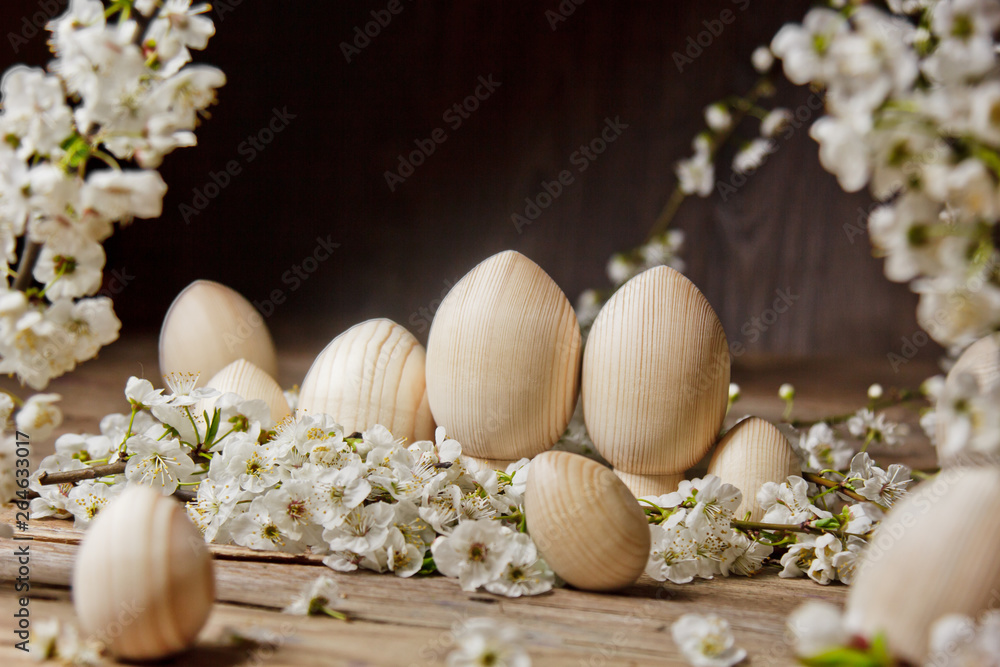 wooden easter eggs among flowering cherry branches on a rustic table. symbolic composition of the spring holiday for a gift card. copy space. close up. petals of white flowers. the rebirth of nature wooden easter eggs among flowering cherry branches on a rustic table. symbolic composition of the spring holiday for a gift card. copy space. close up. petals of white flowers. the rebirth of nature