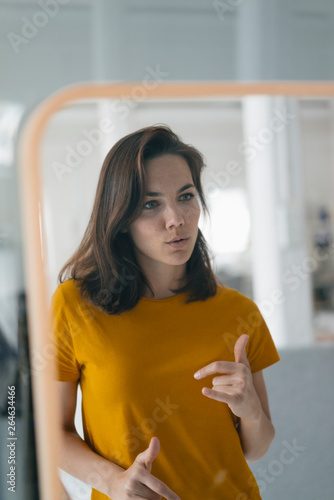 Pretty woman standing in front of mirror, talking