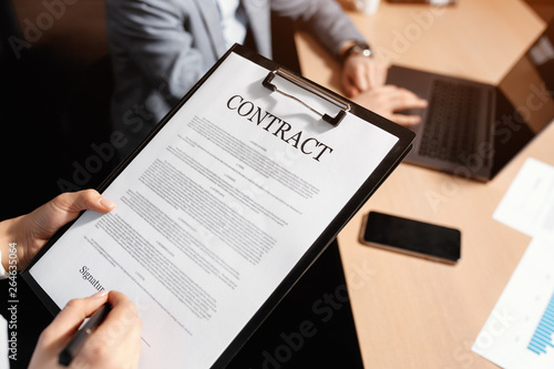 Close-up photo of business woman and man signing a contract in moden office.