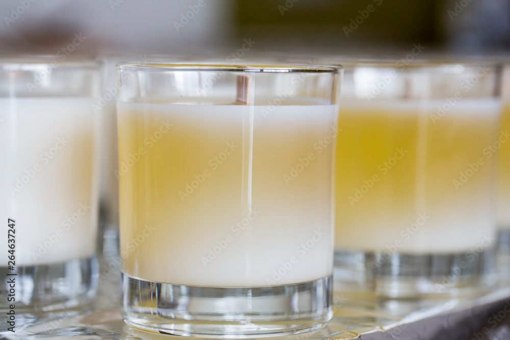 Close up of handmade white and yellow jar candles with wooden wick. Close up of handmade white and yellow jar candles with wooden wick.