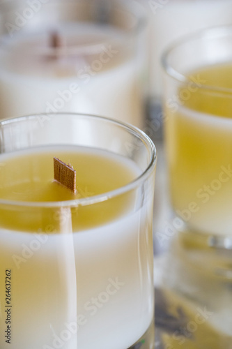 High angle close up of handmade white and yellow jar candles with wooden wick.