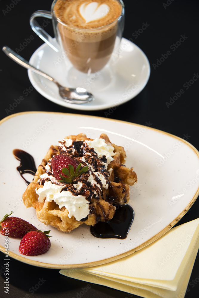Cafe tabletop with sweet pastries, strawberries and cream and coffee latte. Cafe tabletop with sweet pastries, strawberries and cream and coffee latte.