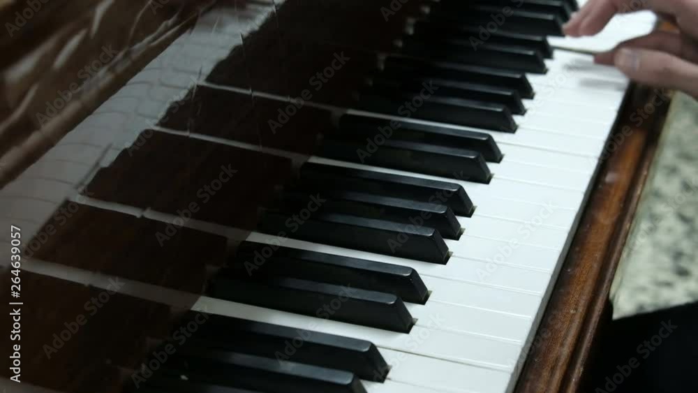 The guy plays the piano. Hands of a young man press the white and black keys of a musical instrument. A young pianist rehearsing a concert.