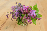 Beautiful lilac flowers in vase, on wooden table