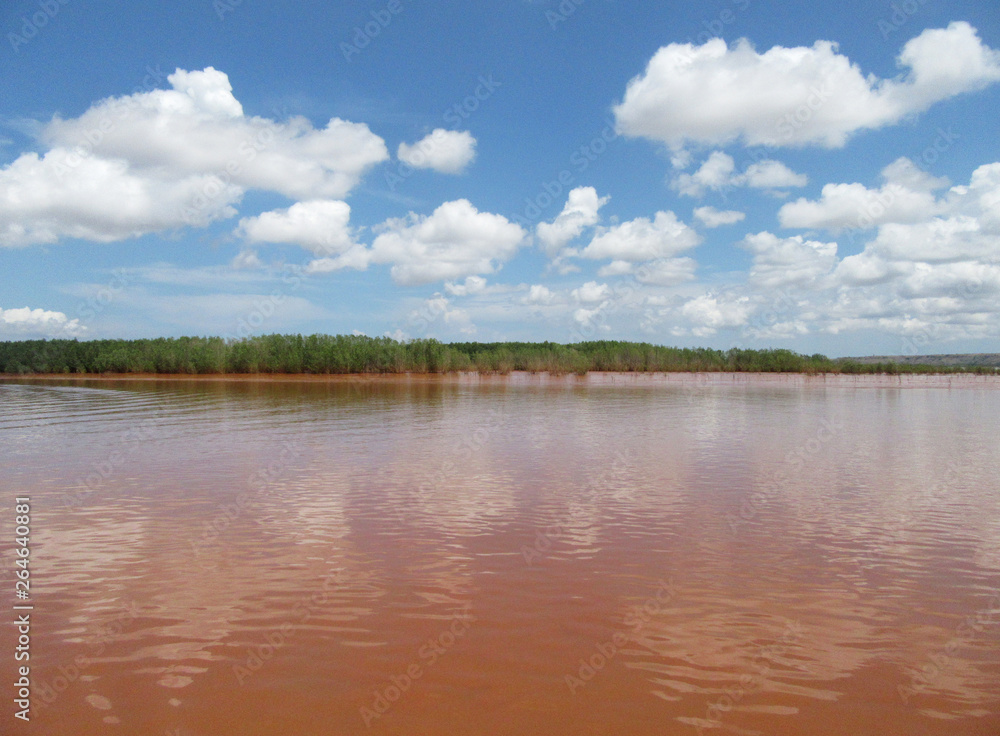 Blue sky with white clouds over the Betsiboka River in the delta in northern Madagascar. The river is red colored due to eroded soil.
