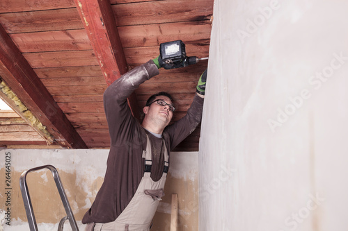 Roof insulation, worker drilling wooden board with a cordless drill photo