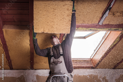 Roof insulation, worker filling pitched roof with wood fiber insulation photo