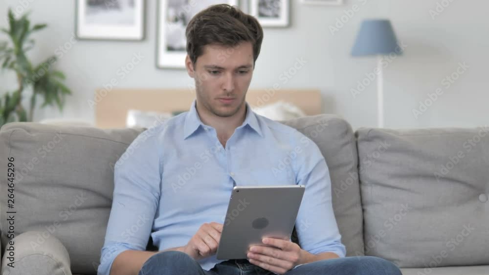 Handsome Young Man Browsing Internet on Tablet Handsome Young Man Browsing Internet on Tablet