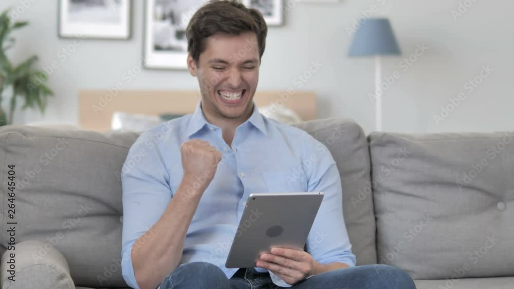Relaxing Handsome Young Man Celebrating Success on Tablet Relaxing Handsome Young Man Celebrating Success on Tablet