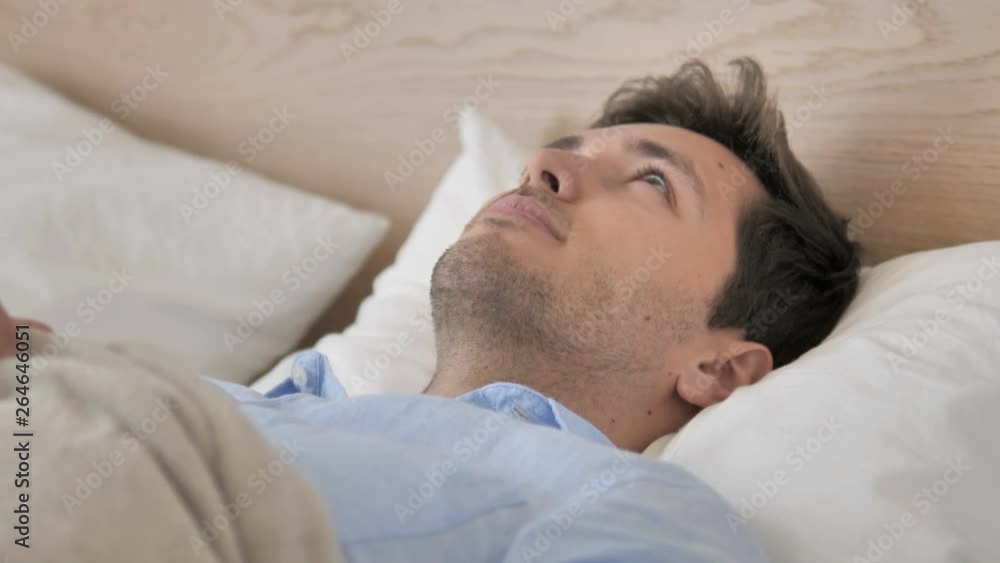 Pensive Young Man Thinking while Lying in Bed Pensive Young Man Thinking while Lying in Bed