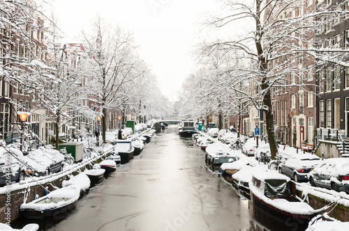 Snow covered Amsterdam canal in cold winter. Amsterdam is the capital of the Netherlands.