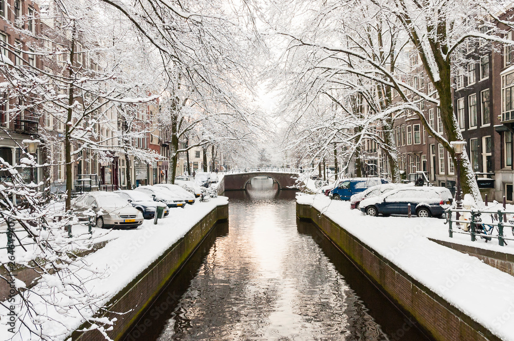 Obraz premium Snow covered Amsterdam canal in cold winter. Amsterdam is the capital of the Netherlands.
