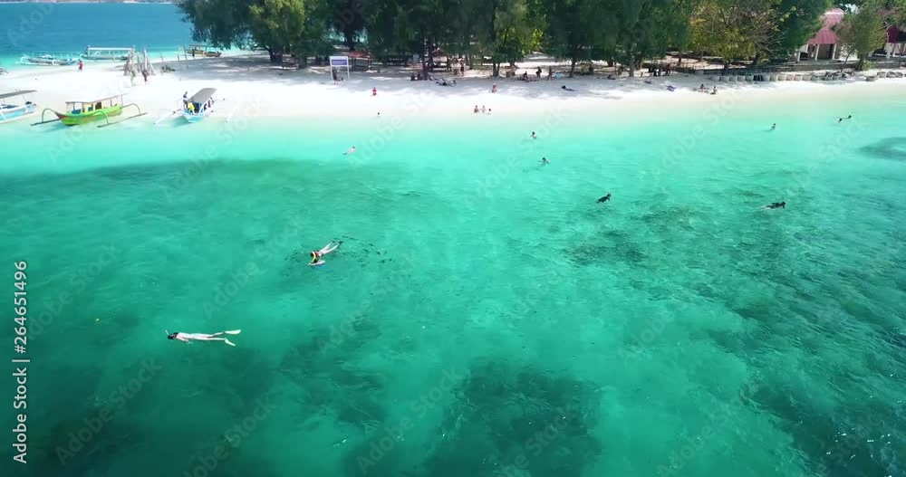 LOMBOK, Indonesia - April 22, 2019: Beautiful aerial view of tourists snorkeling on turquoise water in Gili Nanggu Island at Lombok. Shot in 4k resolution from a drone flying from right to left LOMBOK, Indonesia - April 22, 2019: Beautiful aerial view of tourists snorkeling on turquoise water in Gili Nanggu Island at Lombok. Shot in 4k resolution from a drone flying from right to left