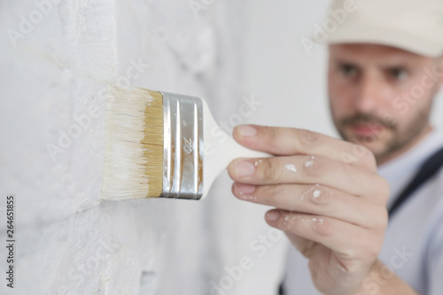 Painting a white brick wall with a paint brush photo
