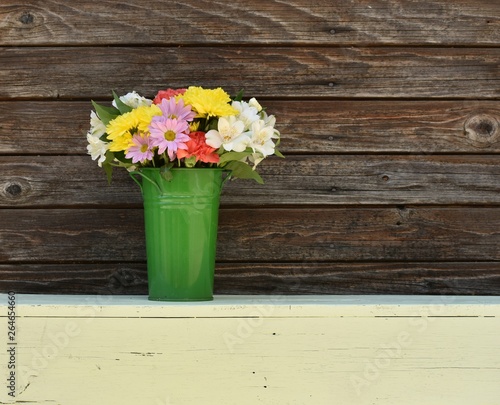 Spring flowers in green metal bucket vase 