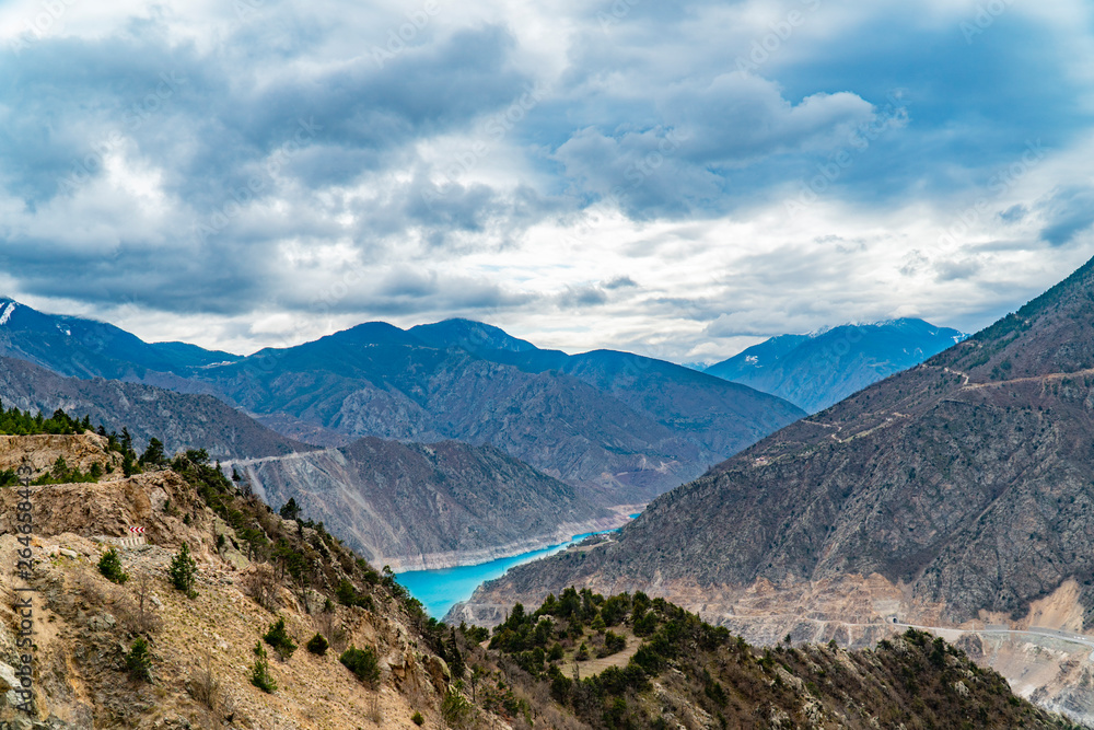 The fantastic view of river with mountains under a blue sky with clouds.