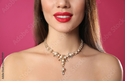 Beautiful woman with stylish jewelry on color background, closeup