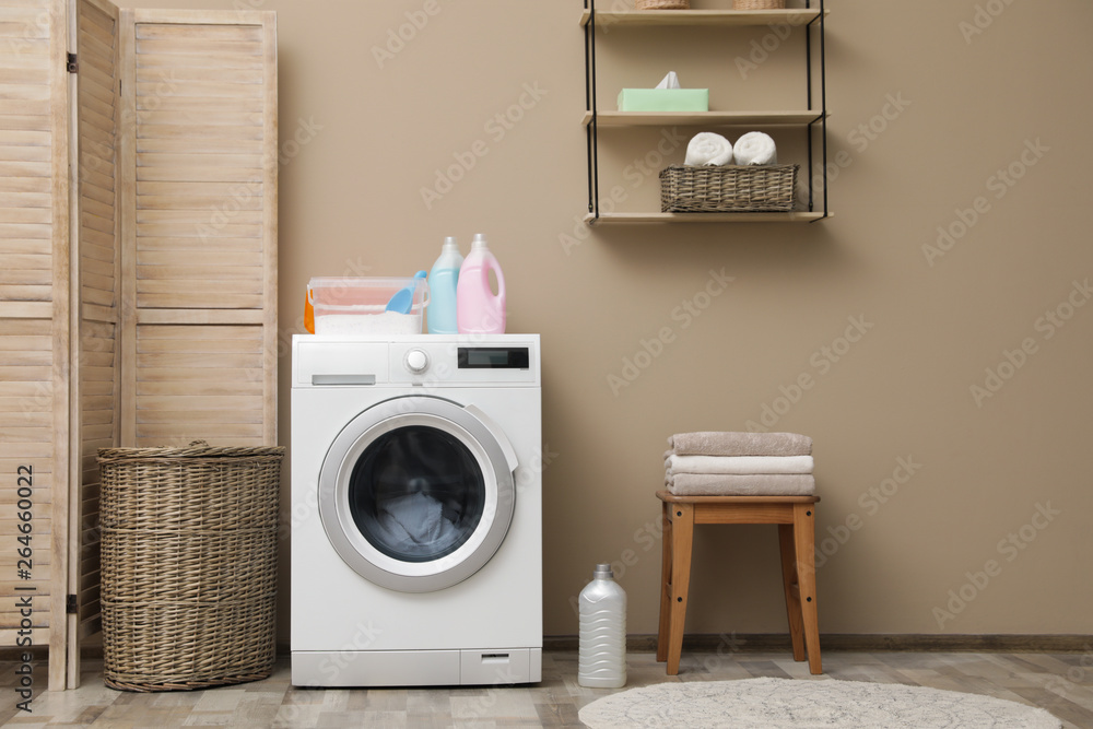 Modern washing machine near color wall in laundry room interior, space for text