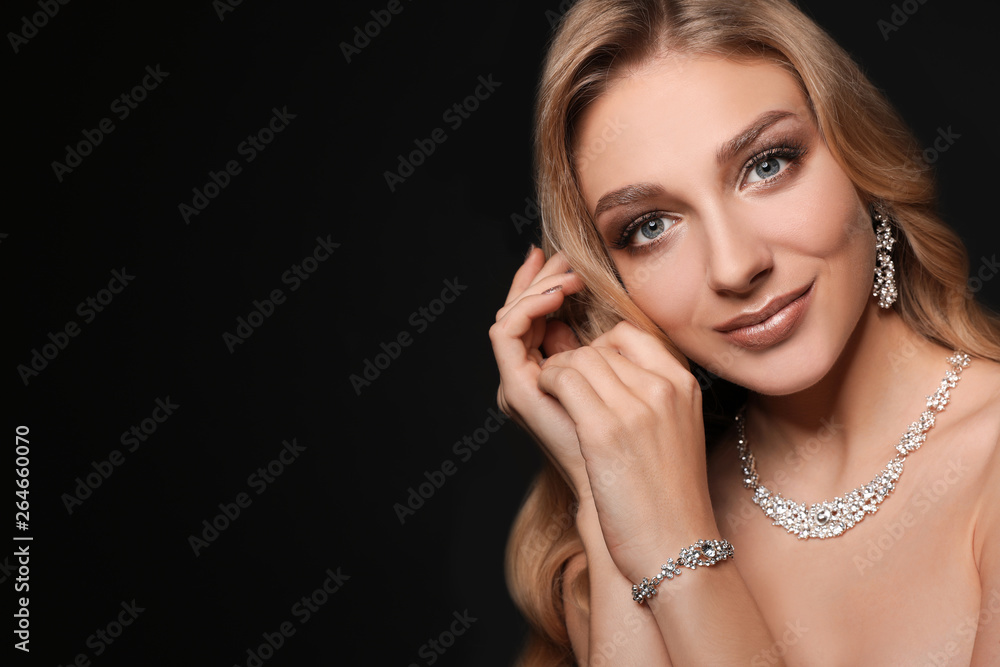 Obraz premium Beautiful young woman with elegant jewelry on dark background. Space for text