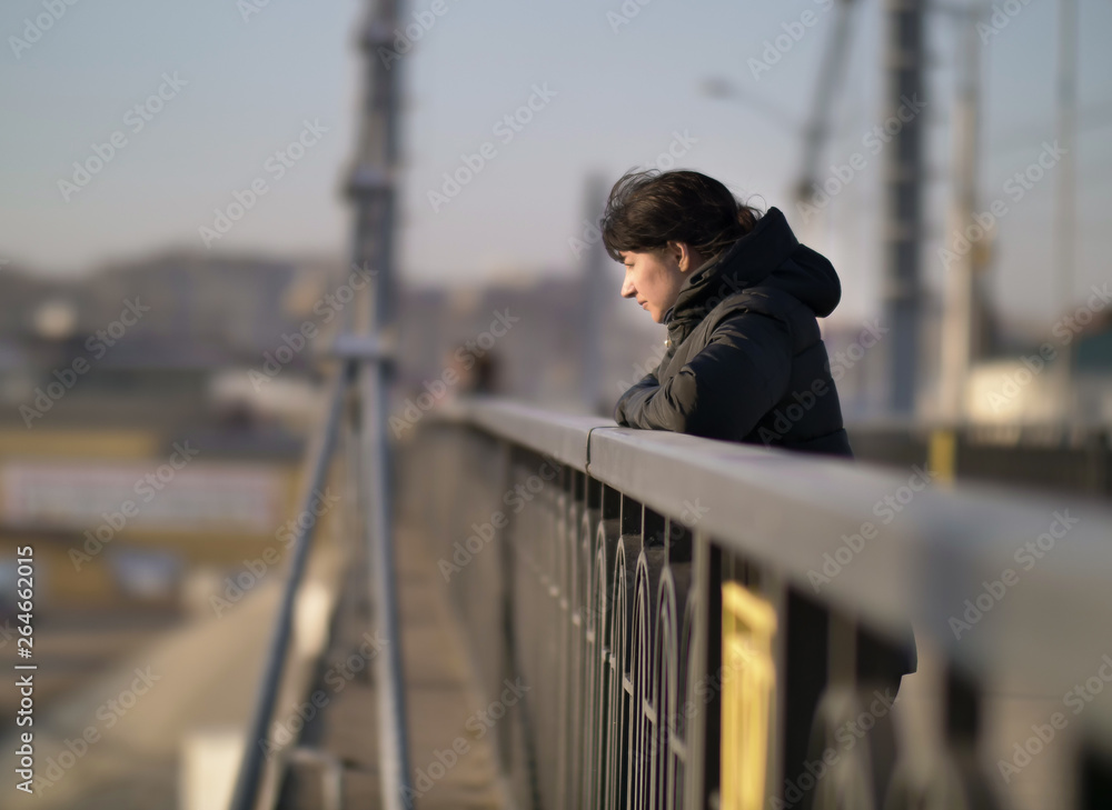 Lonely young girl stands on the bridge on a sunny day Lonely young girl stands on the bridge on a sunny day