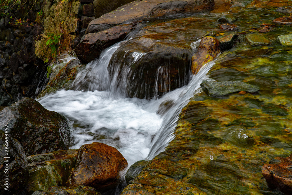 Fantastic landscape view of waterfall flowing around rocks with greens and stones in long exposure. Fantastic landscape view of waterfall flowing around rocks with greens and stones in long exposure.