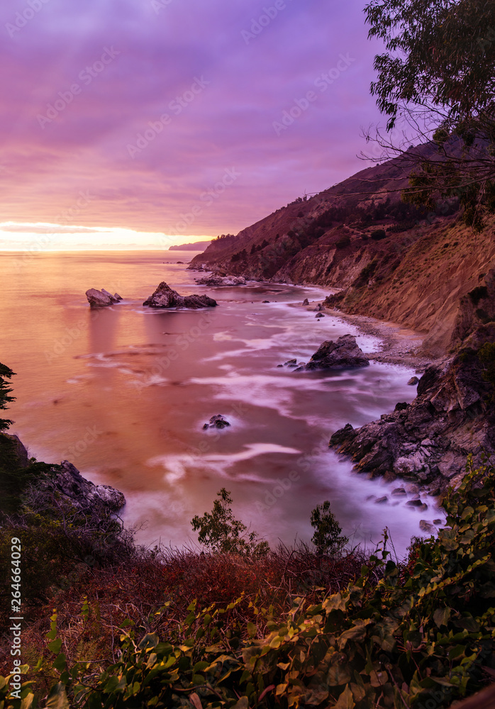 Big Sur California coastline from Julia Pfeiffer Burns State Park near Monterey. This stunning sunset shot captures the sun setting on the beautiful Pacific ocean on a colorful summer afternoon. Big Sur California coastline from Julia Pfeiffer Burns State Park near Monterey. This stunning sunset shot captures the sun setting on the beautiful Pacific ocean on a colorful summer afternoon.