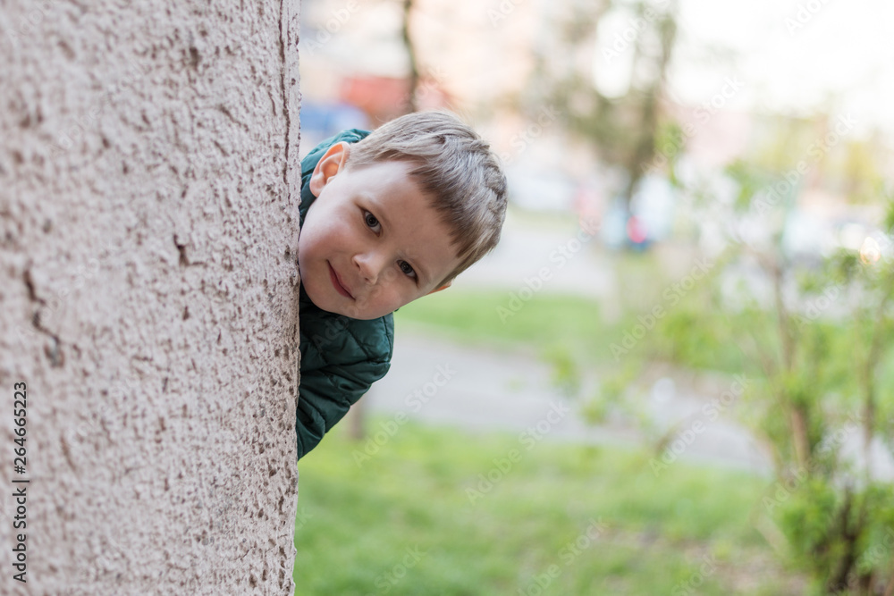 A little boy looks out from behind the wall. A little boy looks out from behind the wall.