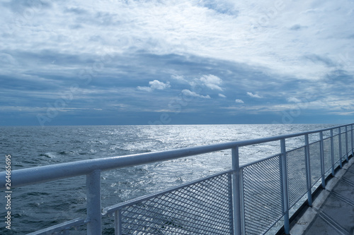 Railing on a ship's upper deck, converging with the horizon and stunning blue sky in the distance © Casual-T