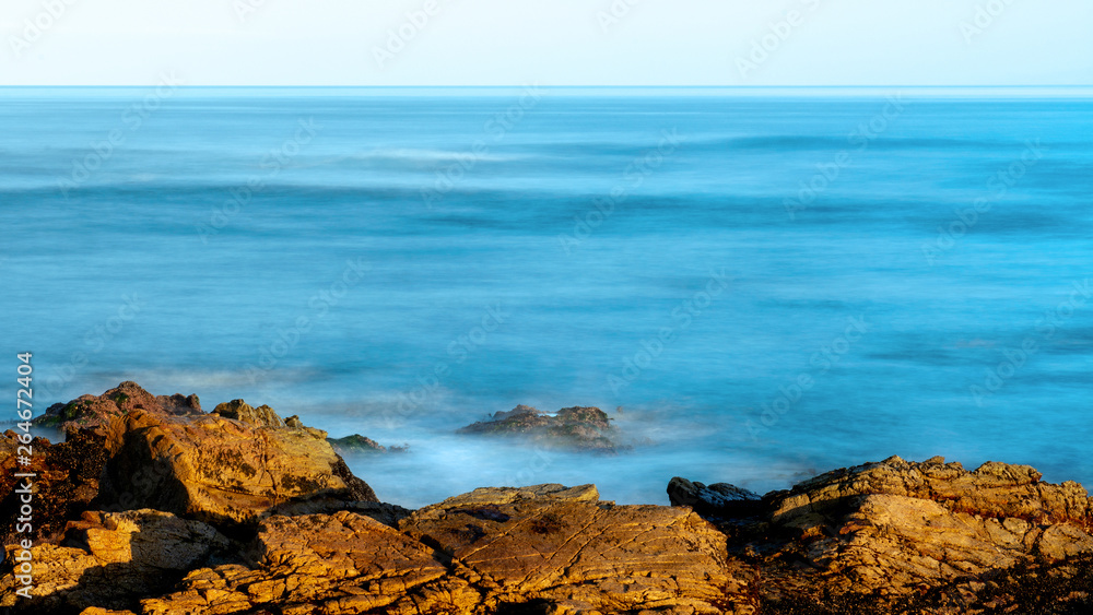 Long exposure view of the ocean near Pebble Beach, Monterey, California,, USA, on the 17-mile drive route in the winter of 2019, in the sunrise- large blue copy space Long exposure view of the ocean near Pebble Beach, Monterey, California,, USA, on the 17-mile drive route in the winter of 2019, in the sunrise- large blue copy space