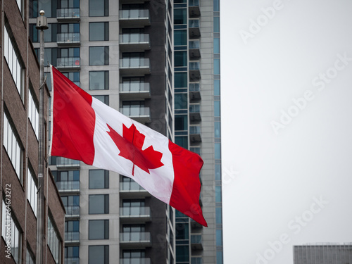 Canadian flag in front of a residential condo building in Montreal, Quebec, Canada. Montreal is main economic and business hubs of Quebec and one of biggest of North America