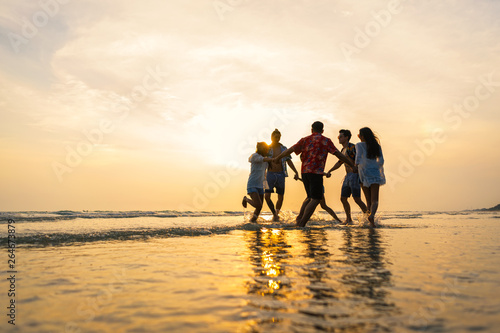A group of male and female friends who play fun on the sea beach amid the sunset. photo