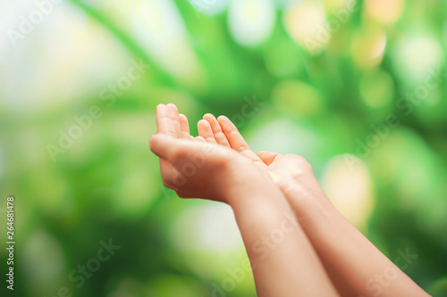 Woman hands place together like praying in front of nature green  background. © ant
