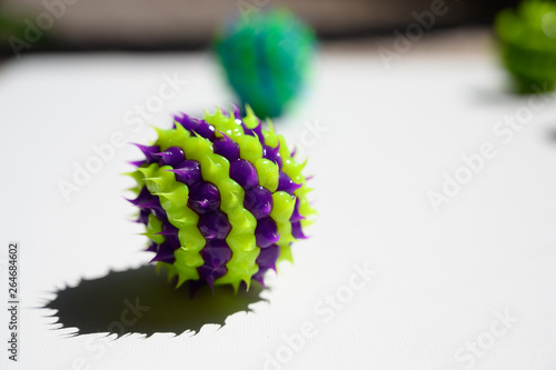 purple and green striped ball with spikes on white surface photo