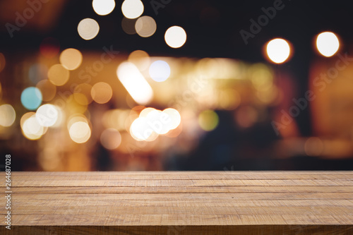 Empty wooden table in front of abstract blurred bokeh background of restaurant.