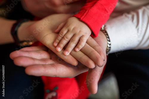Father and mother holding kid hand. Child hand closeup into parents