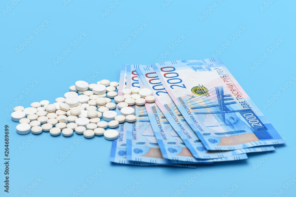 Russian two thousand rubles and round white pills on a blue background Russian two thousand rubles and round white pills on a blue background