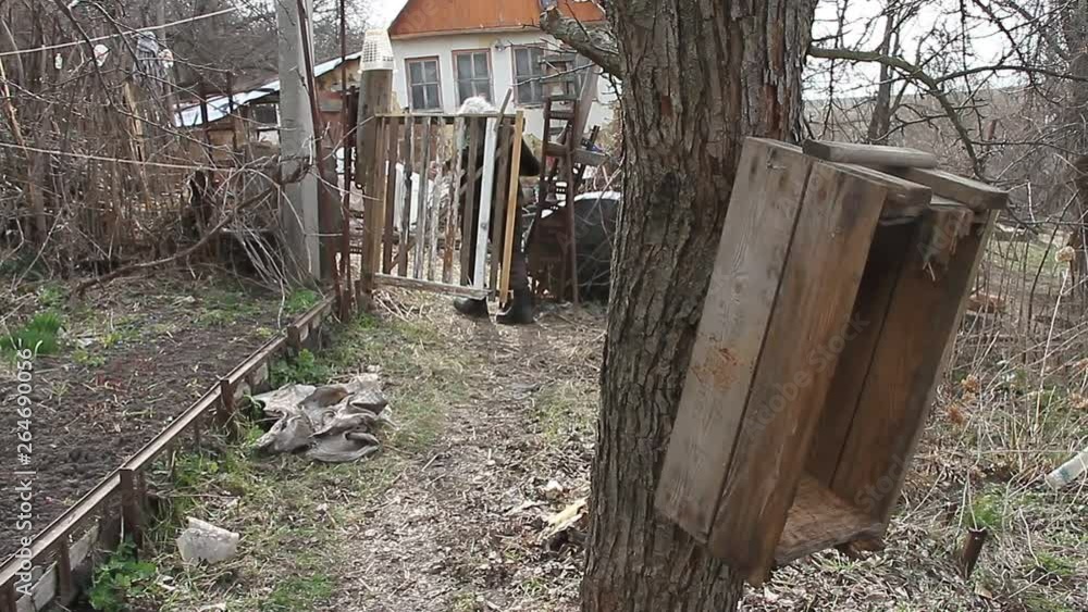The poor old grandfather walks through the patch of land to the rickety gate and the old collapsed house. Life in an abandoned village. The poor old grandfather walks through the patch of land to the rickety gate and the old collapsed house. Life in an abandoned village.