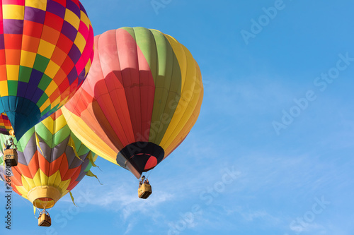 Three multi colored hot air balloons flying close to each othe over blue sky