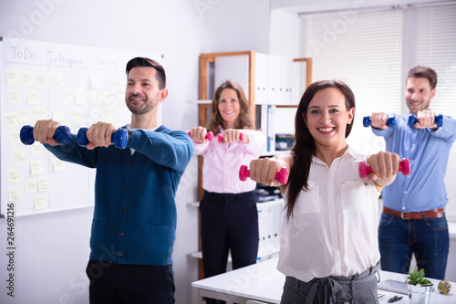 Fototapeta Naklejka Na Ścianę i Meble -  Businesspeople Exercising With Dumbbells