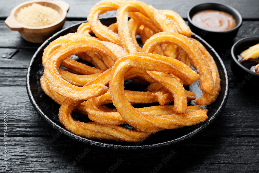 Churros with sugar and chocolate sauce on black wooden background. Churros with sugar and chocolate sauce on black wooden background.