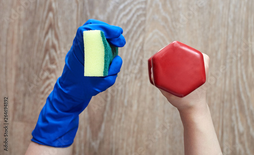 One hand with dumbbells, the other hand in a glove with a sponge. The choice between sports and homework for housewives.