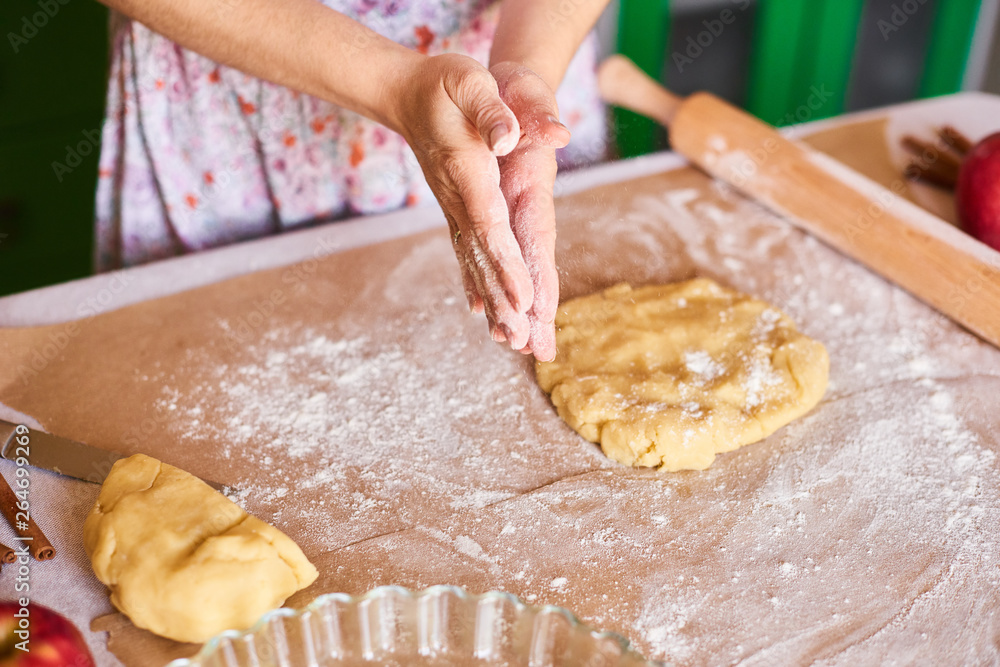 Hands working with dough preparation recipe bread. Female hands making dough for pizza. Woman's hands roll the dough. Mother rolls dough on the kitchen board with a rolling pin Hands working with dough preparation recipe bread. Female hands making dough for pizza. Woman's hands roll the dough. Mother rolls dough on the kitchen board with a rolling pin