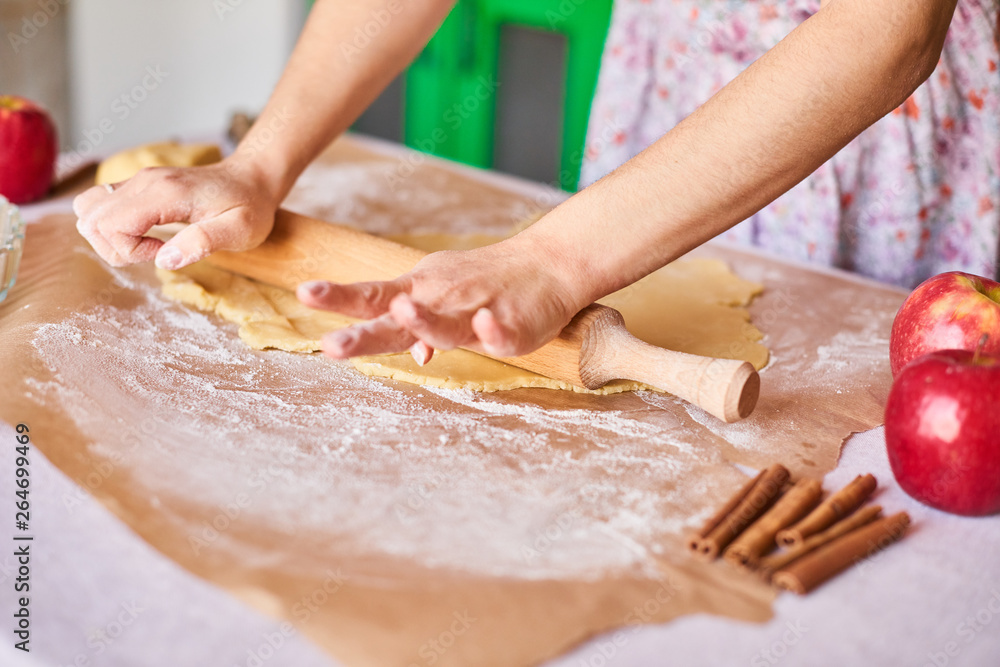 Hands working with dough preparation recipe bread. Female hands making dough for apple pie. Woman's hands roll the dough. Mother rolls dough on the kitchen board with a rolling pin
