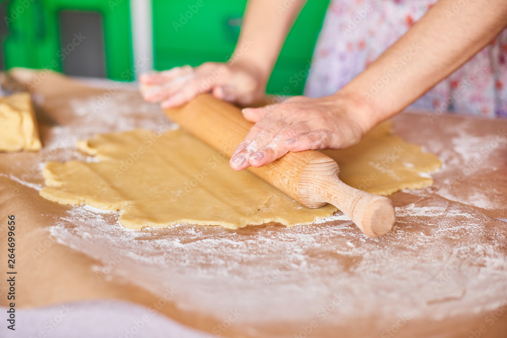 Hands working with dough preparation recipe bread. Female hands making dough for pizza. Woman's hands roll the dough. Mother rolls dough on the kitchen board with a rolling pin