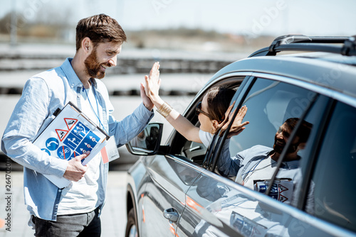 Canvastavla Instructor giving a five to a woman driver sitting in the car while learning to