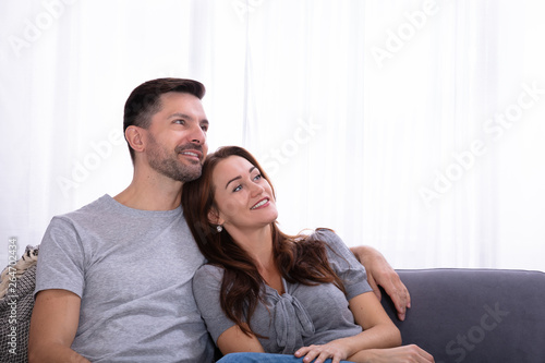 Contemplated Couple Sitting On Couch At Home