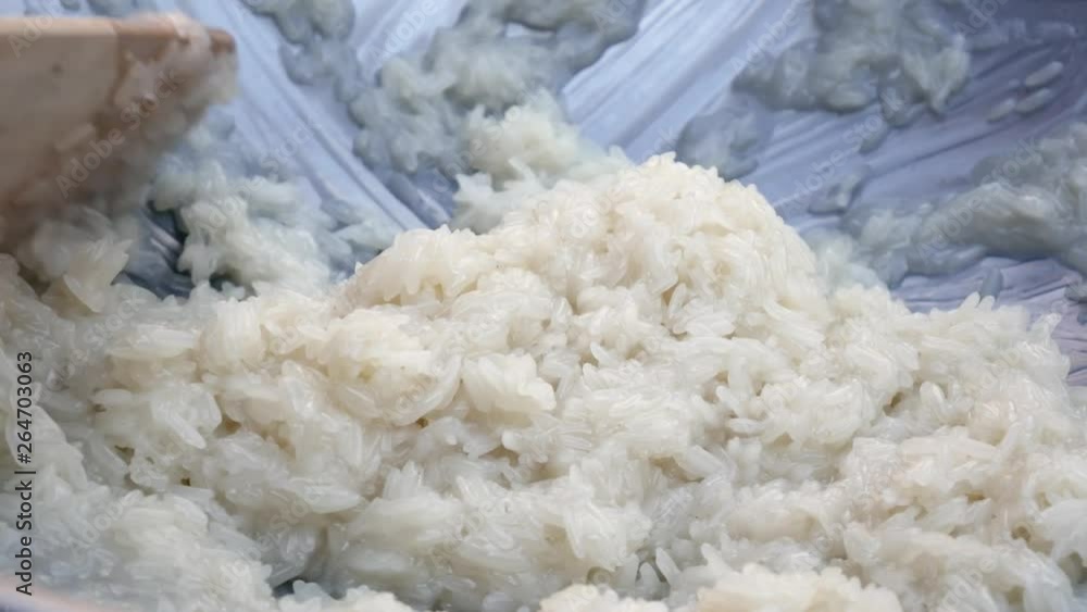 Male hand stir rice with coconut milk in wok. Step by step cooking Thai sticky rice. Thai cuisine. Closeup. 4k Male hand stir rice with coconut milk in wok. Step by step cooking Thai sticky rice. Thai cuisine. Closeup. 4k